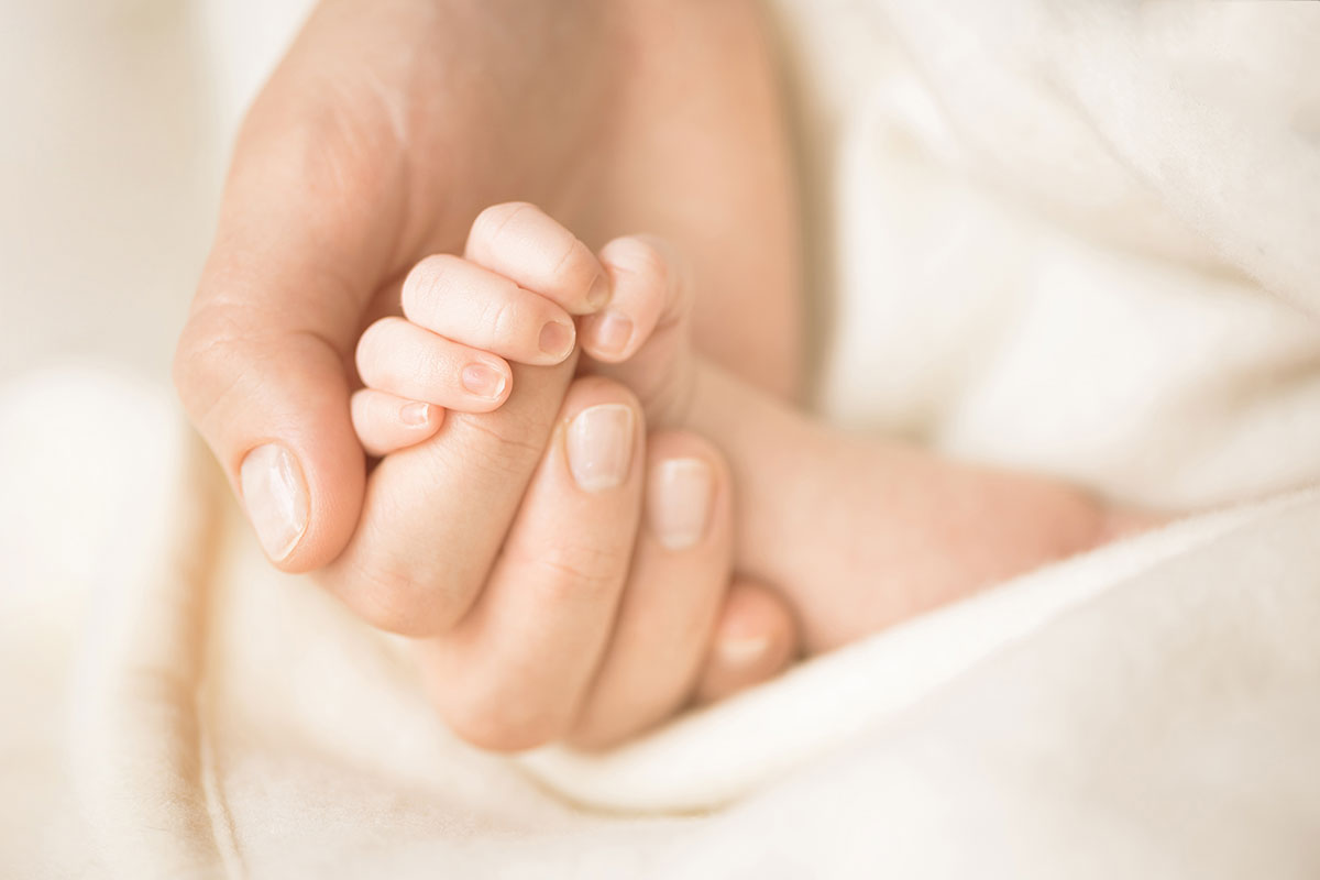 Female hand holding her newborn baby's hand. Mom with her child. Maternity, family, birth concept. Copy space for your text. Banner.