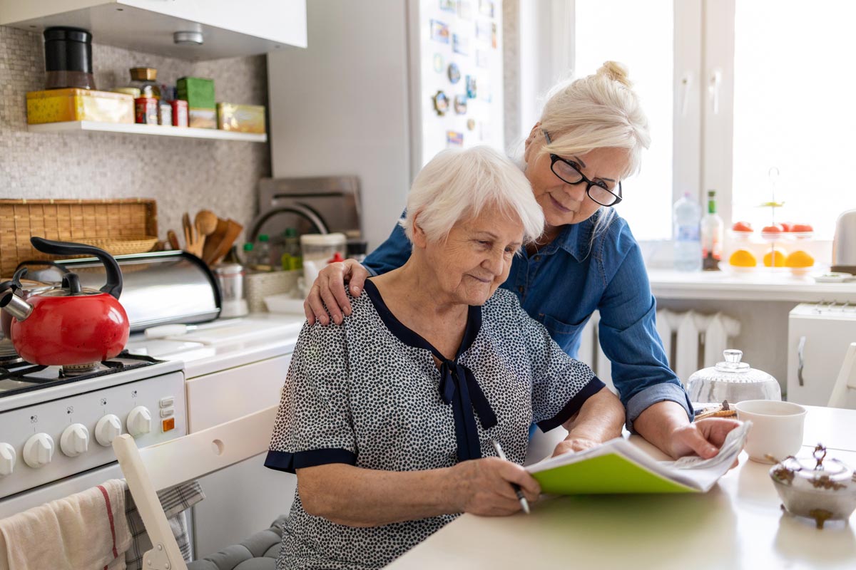 Mature woman helping elderly woman read