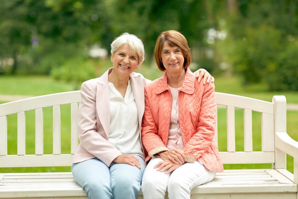 Two women sitting on bench at summer park